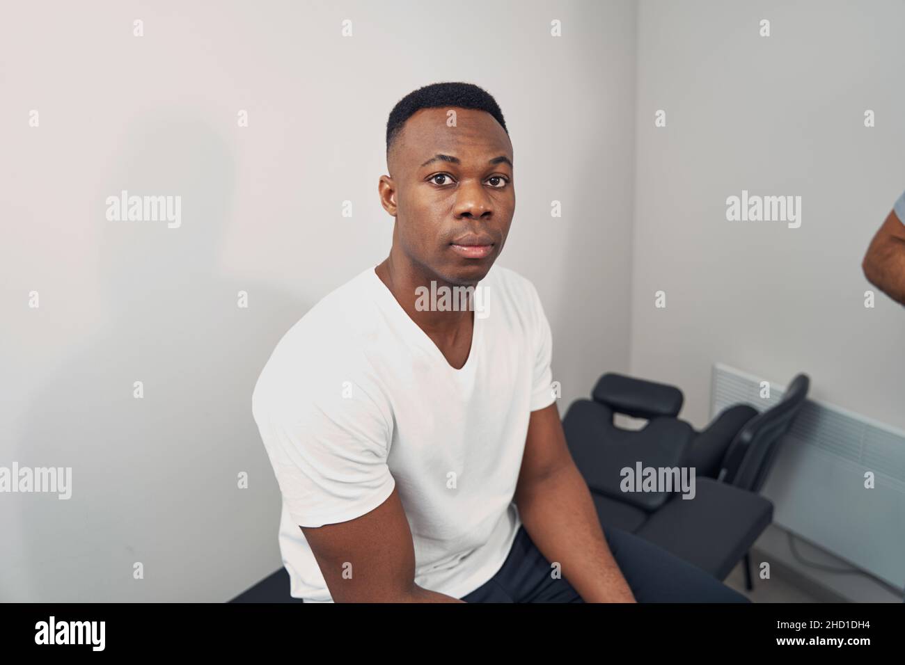 Serene young man seated in physiotherapist office Stock Photo