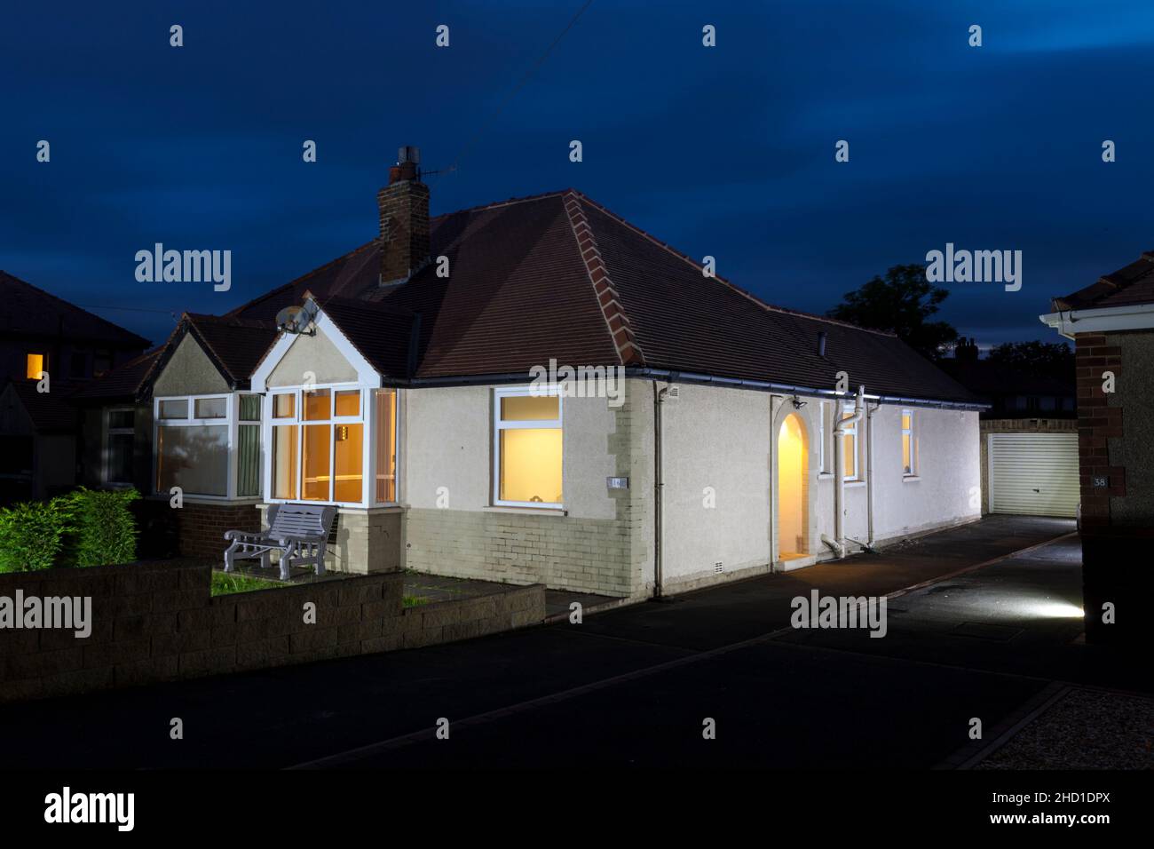 Bungalow on a street in Lancashire England lit up with lights at dusk Stock Photo