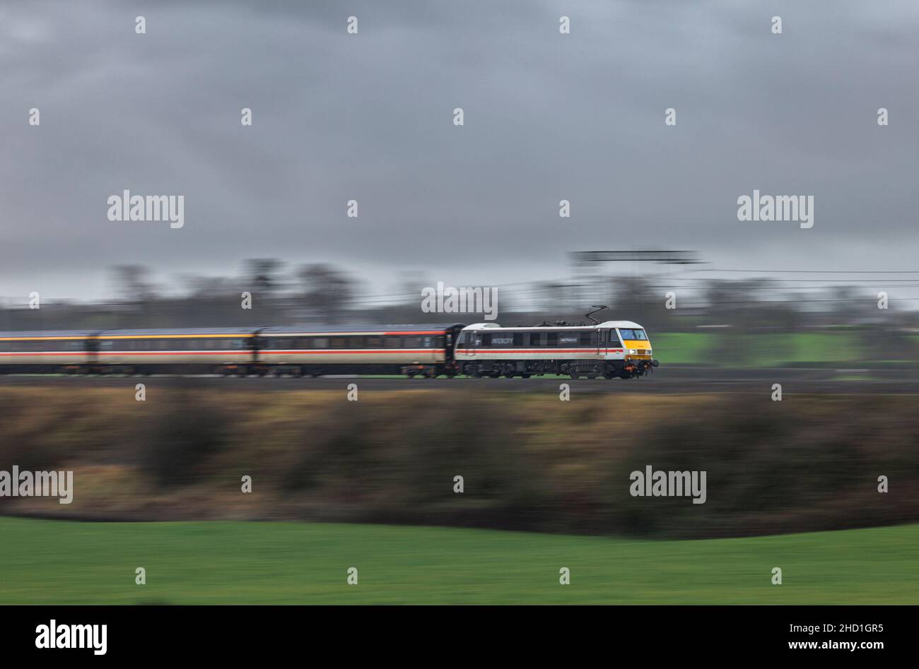 Intercity livery class 90 electric locomotive 90002 hauling a Intercity charter train on the west coast mainline panned at high speed with motion blur Stock Photo