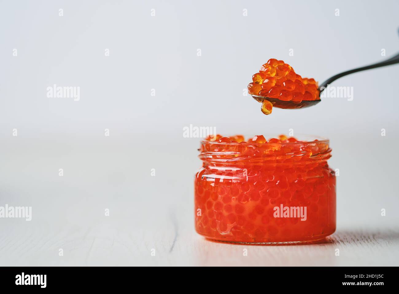 Photo with shallow depth of field of open jar with red caviar and a spoon above it Stock Photo