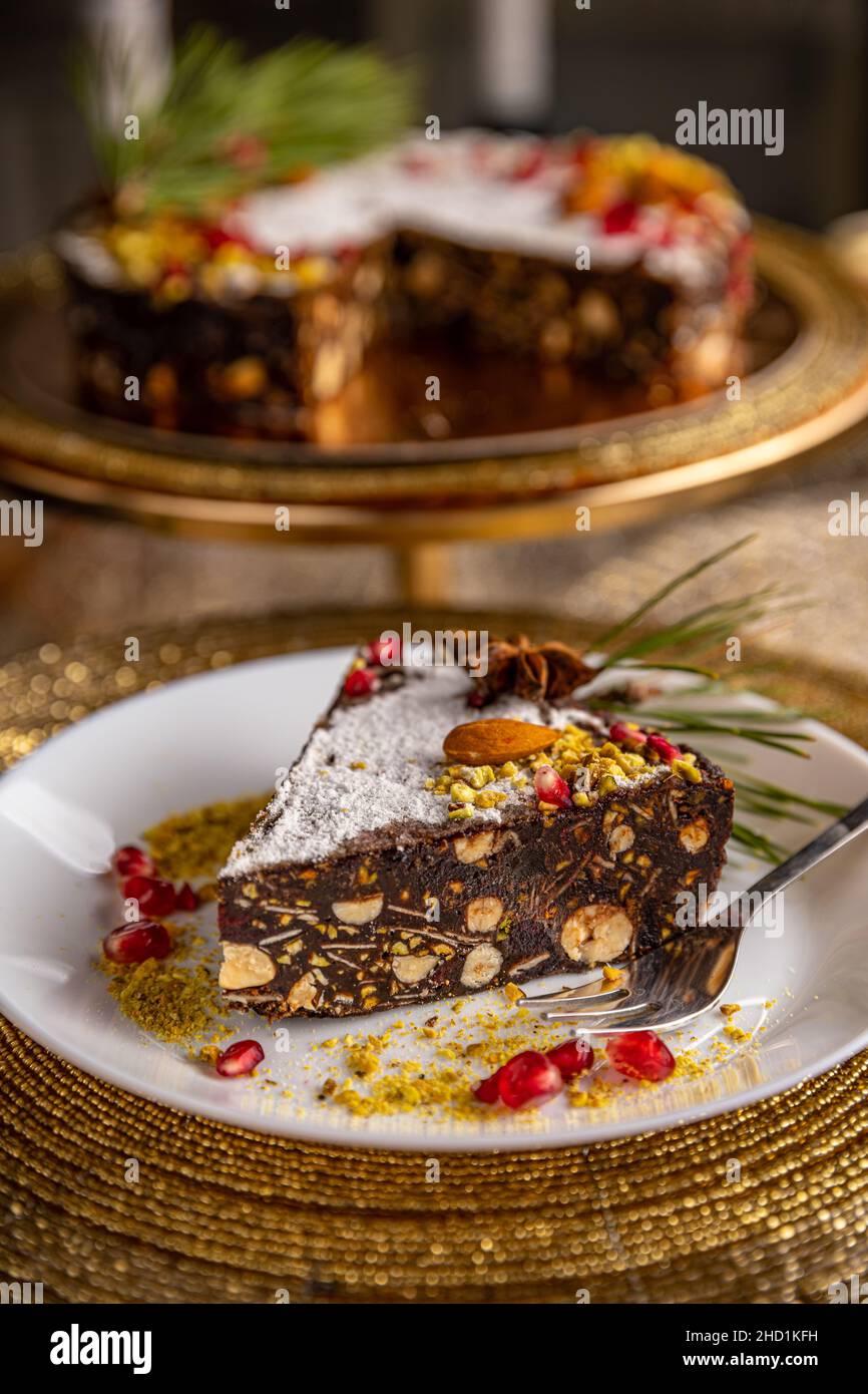 Slice of raw vegan chocolate cake with pistachio, almond and nuts for Christmas table Stock Photo