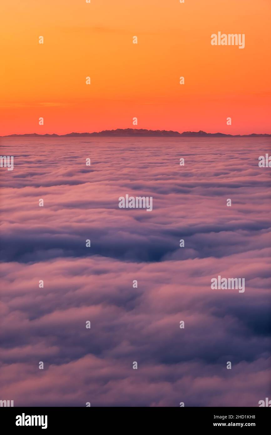 The French and Italian Alps silhouetted against an orange sky above a cloud inversion viewed from Corsica at sunset Stock Photo