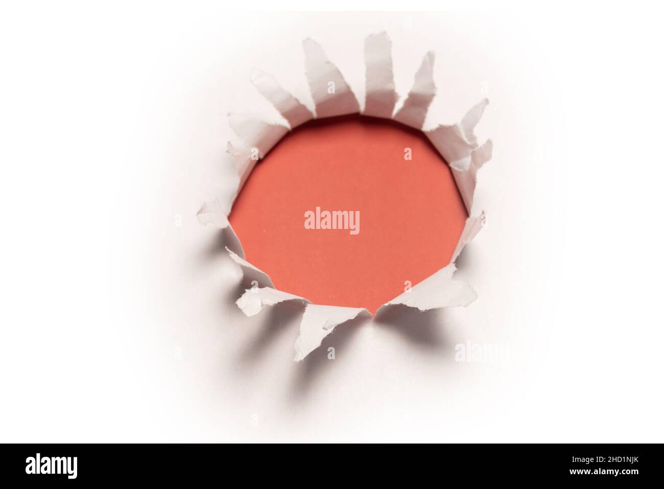 A hole in a white paper on a red background, copy space. Stock Photo