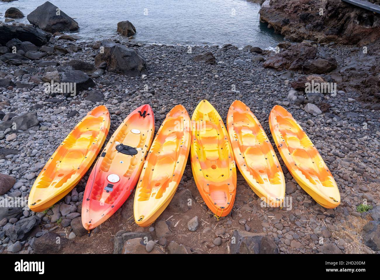 Several colorful kayak lifted on the shore between rocks in Madeira ...