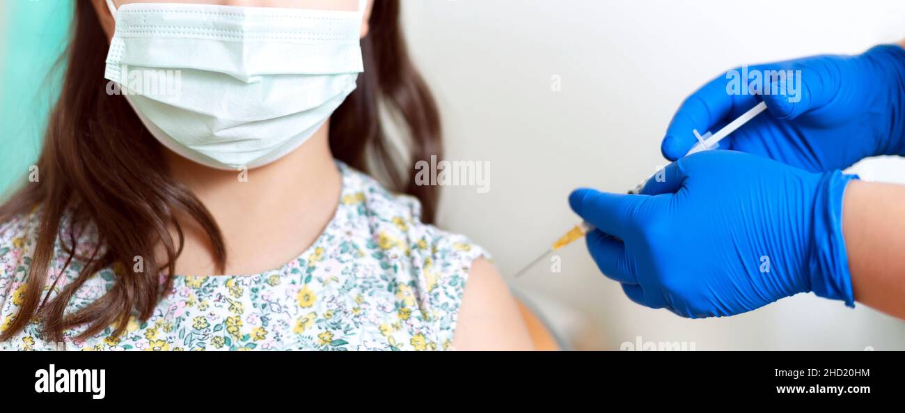 Close-up of an unrecognizable little girl receiving a dose of vaccine. Childhood vaccination campaign. Stock Photo