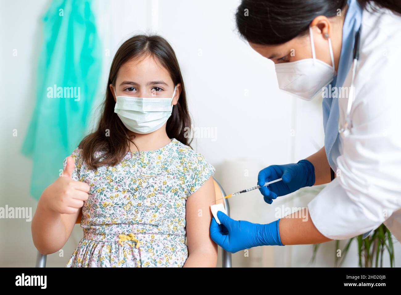 Little caucasian child giving a thumbs up while being vaccinated by a ...