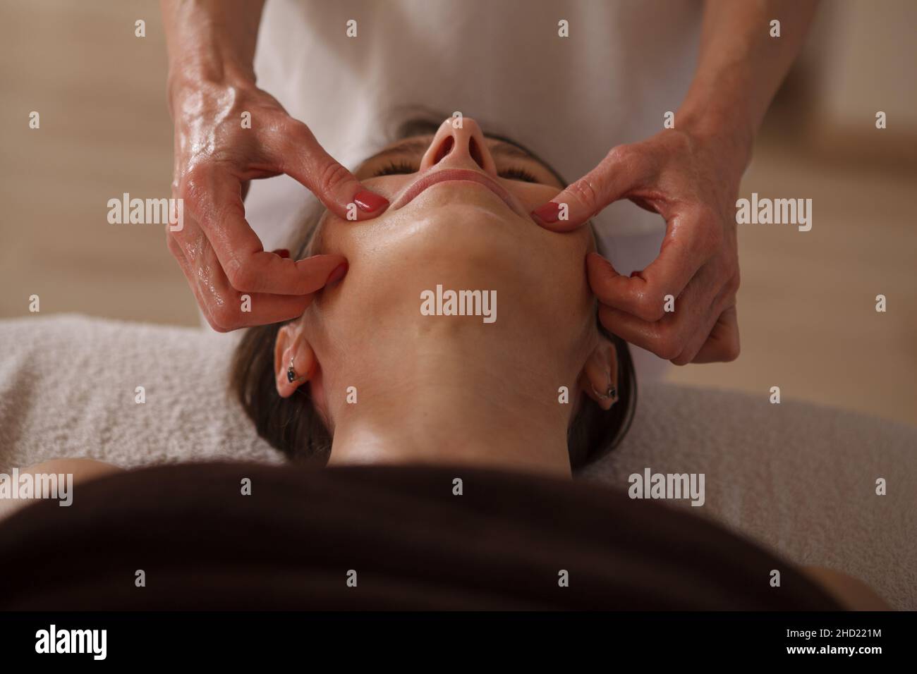 Low angle close up of a woman getting facial massage at spa center by beautician Stock Photo