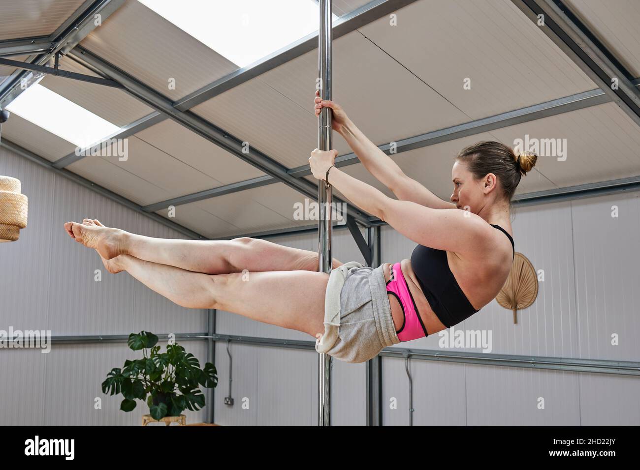 woman suspended in pole dance bar, with good age physique in the 40s Stock Photo