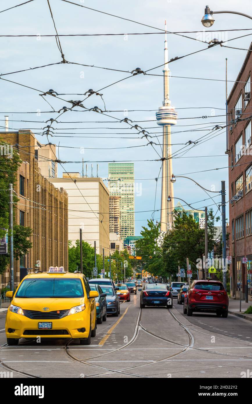 Taxi car driving in the downtown district with the CN Tower in the background. The streetcar cables are seen in the scene. Jan. 2, 2022 Stock Photo