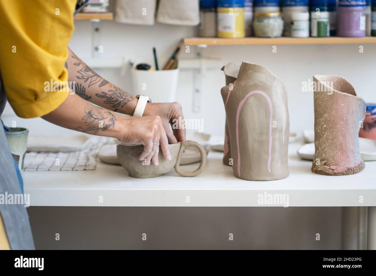 Female ceramist making mug in studio, woman working with clay during pottery masterclass Stock Photo