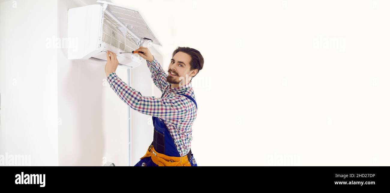 Copy space banner background with happy technician who is fixing wall air conditioner Stock Photo