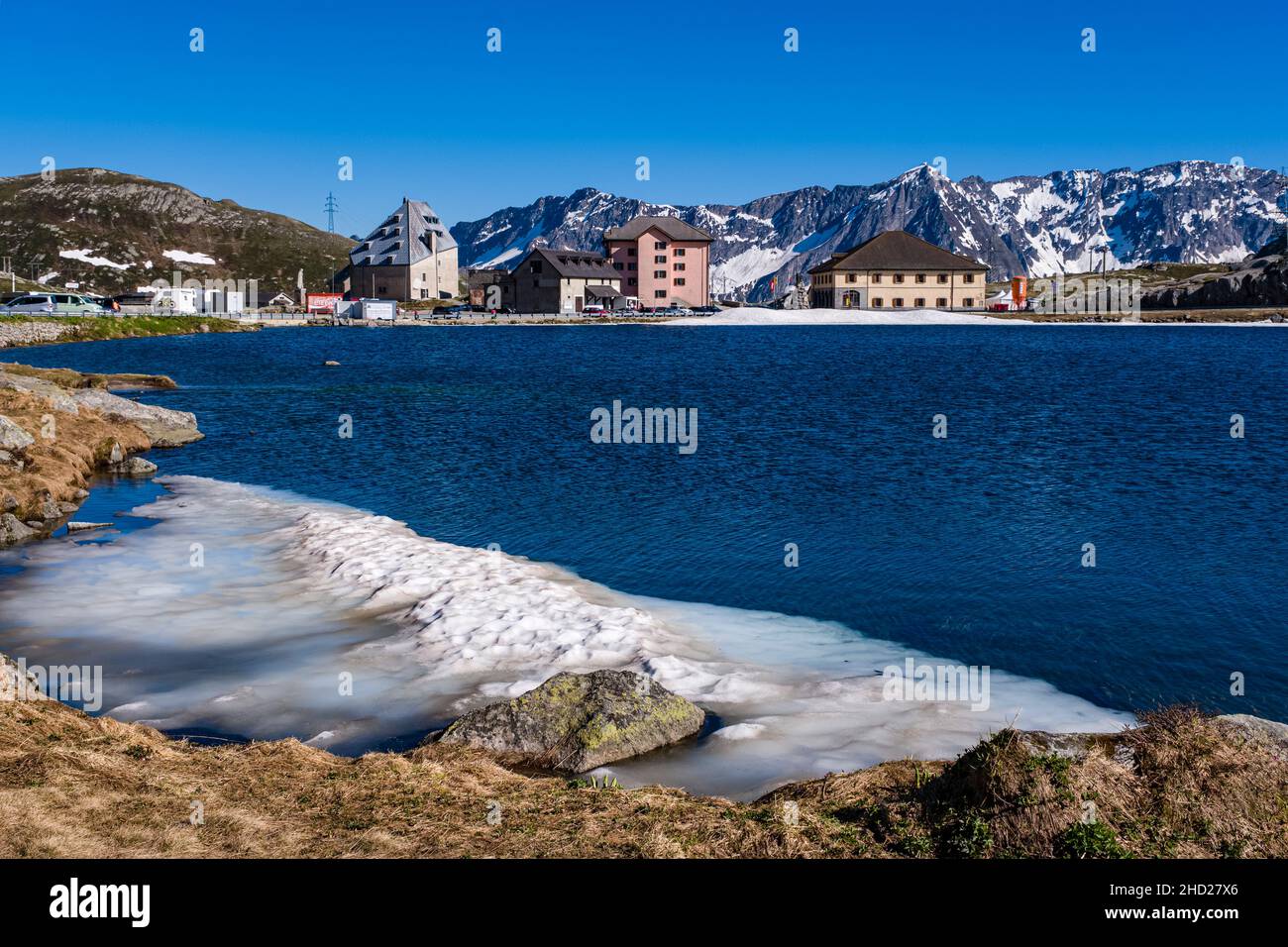 Lakes and buildings, still covered in snow in June, on top of Gotthard Pass at 2106 m, connecting the cantons of Ticino and Uri. Stock Photo