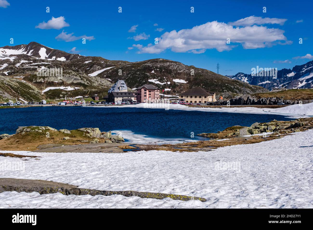 Lakes and buildings, still covered in snow in June, on top of Gotthard Pass at 2106 m, connecting the cantons of Ticino and Uri. Stock Photo