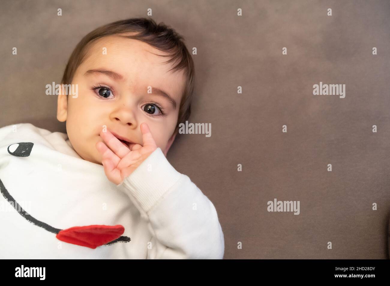 Baby suffering the pain of his first teeth, lying on the sofa at home