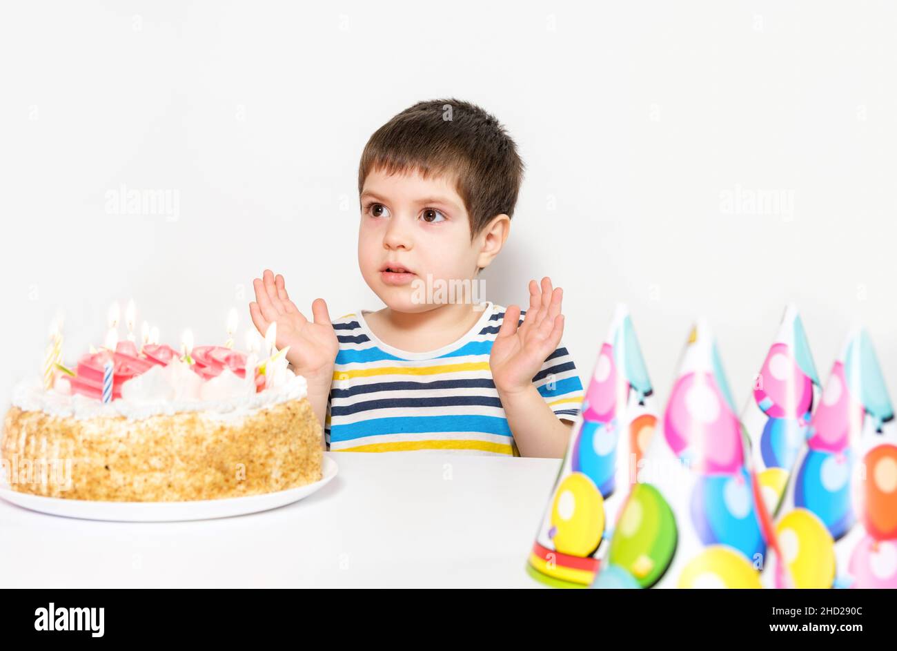 A handsome preschool boy with a cake on his birthday claps his hands on