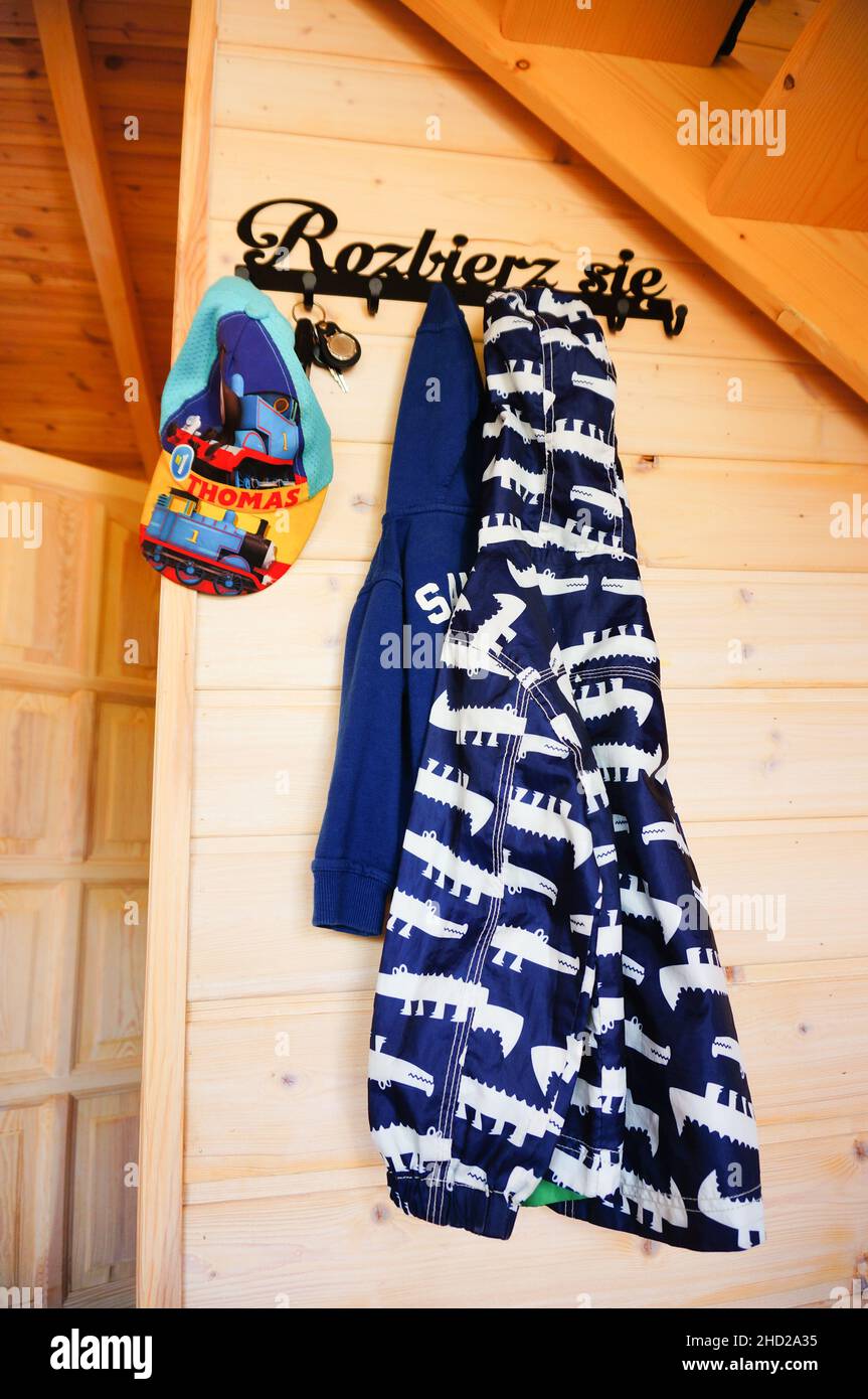 Vertical shot of a hat and a jacket hanging on a wooden wall in a hut in Poland Stock Photo
