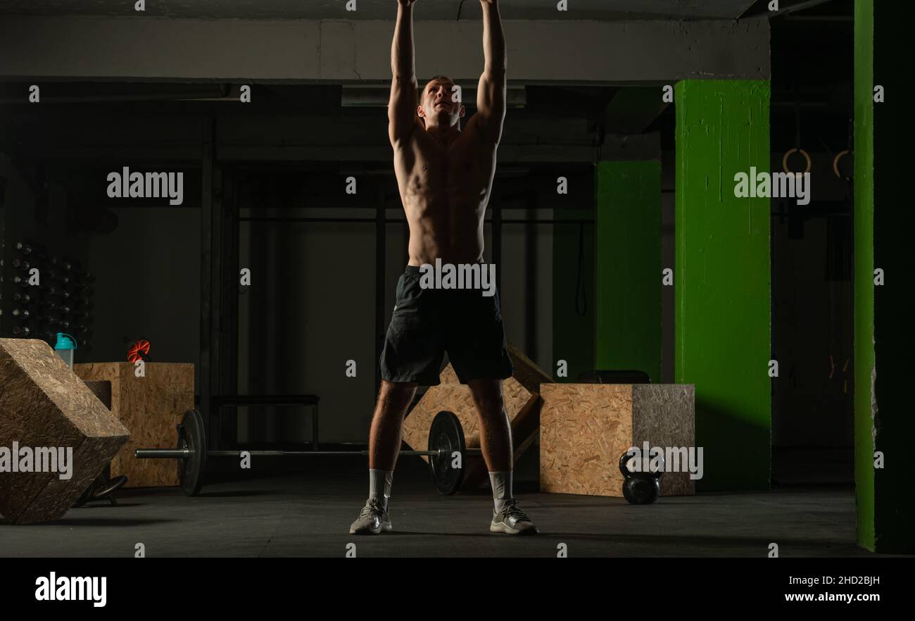 Fit man throwing medicine ball doing ball slam against gym floor or shoulder press exercise