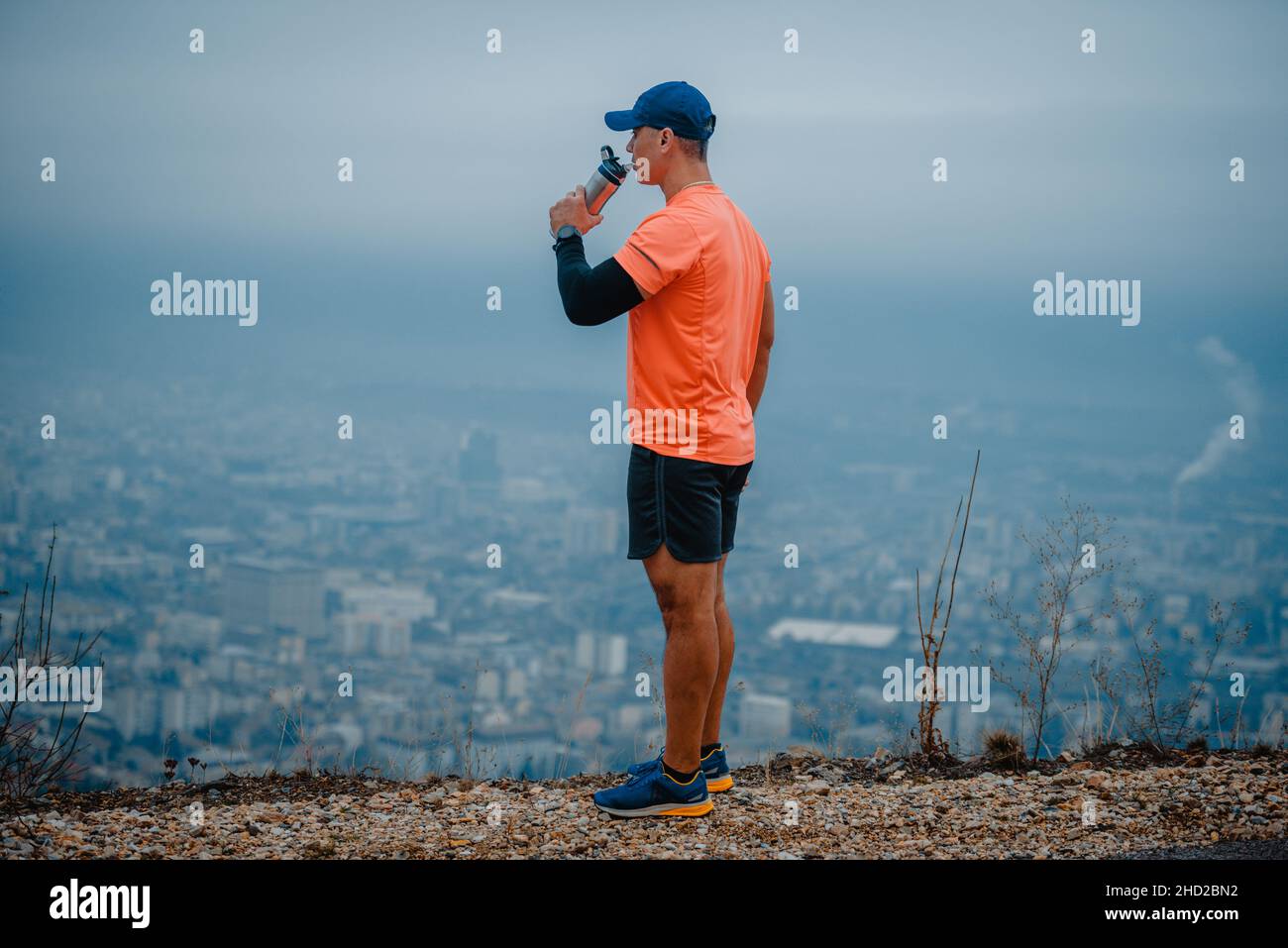 Well built middle aged athlete drinking water and taking a break from running Stock Photo