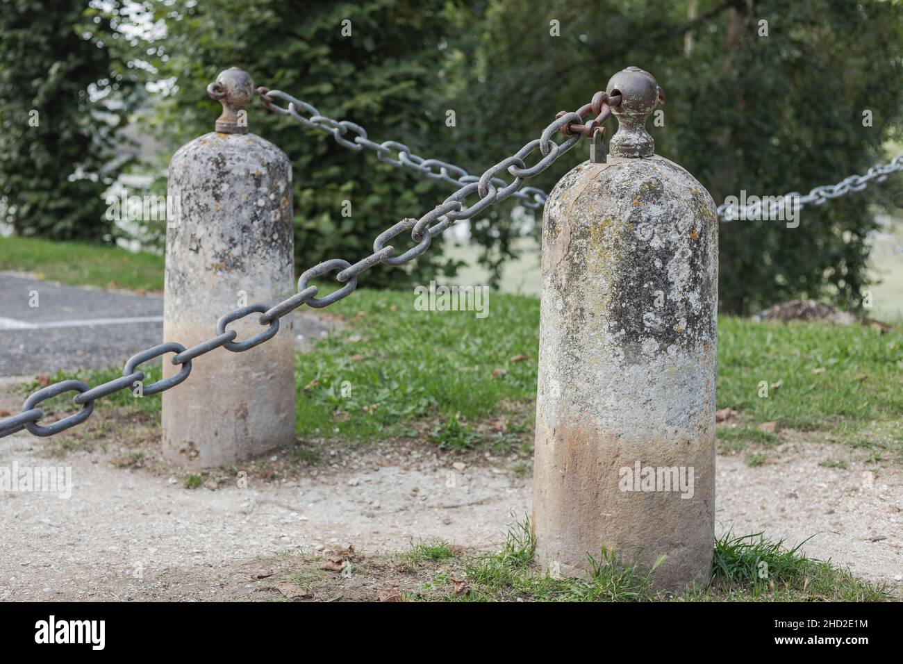 two concrete bollards across a pathway with metal heavy chains which are locked Stock Photo