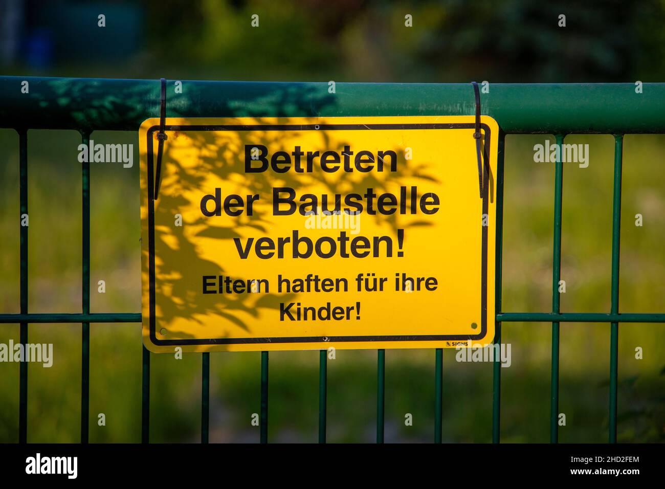 Warning sign on a fence with German text translates into construction site do not enter in English language Stock Photo