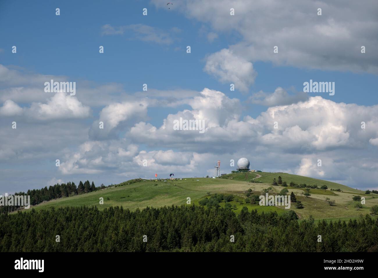 View to the hill Wasserkuppe in nature park Rhön Germany with Radom and paragliding on the ground and in the air. Stock Photo