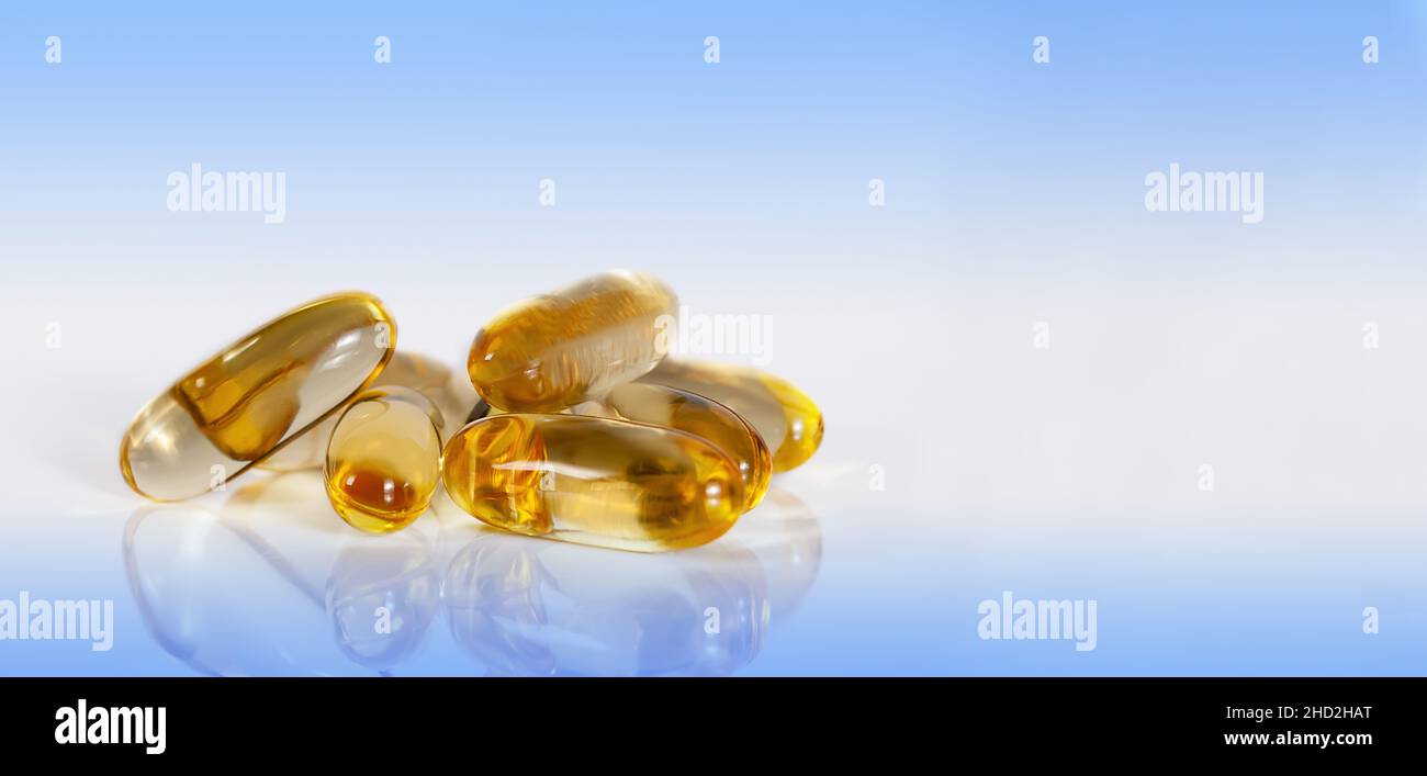 yellow vitamin e fish oil capsule on light blue background with