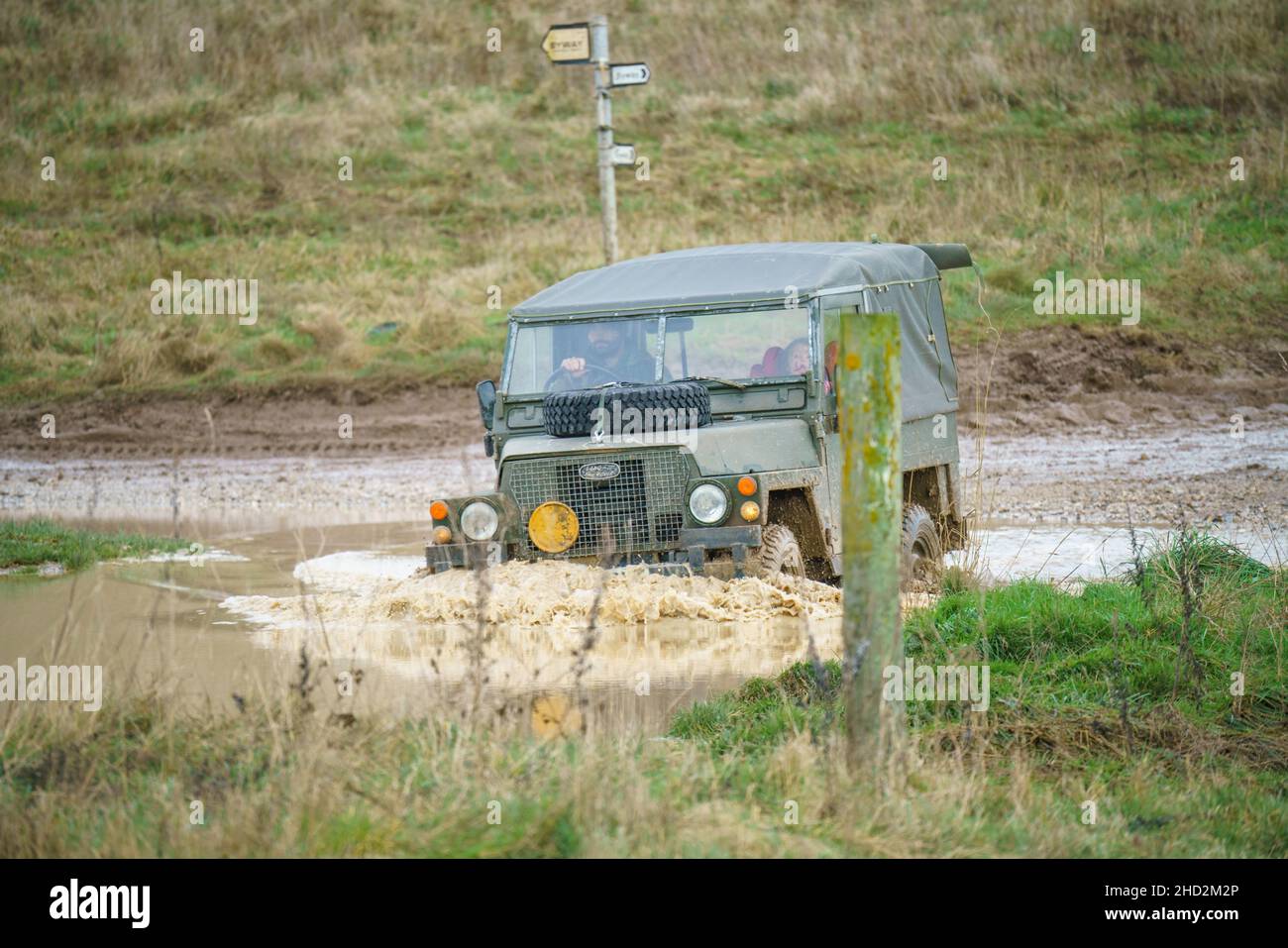 a vintage Land Rover series 2 vehicle driving offroad through deep