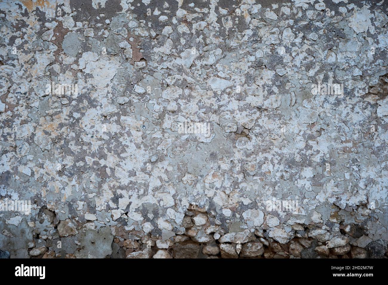 Old traditional limewashed stone wall with peeling plaster, white rustic background or texture Stock Photo