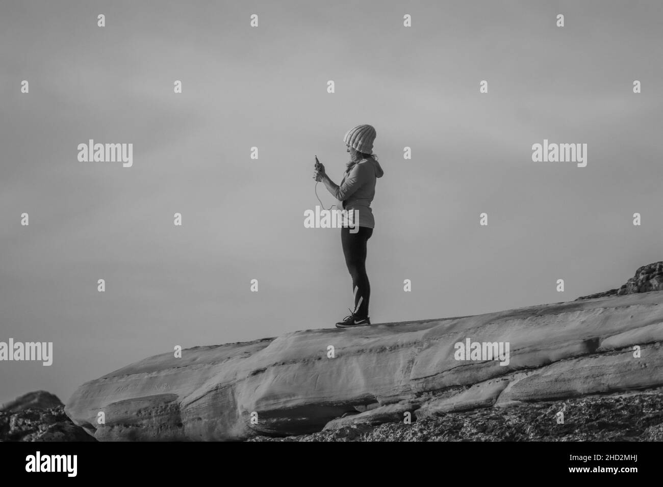 Hipster girl is shooting video of beautiful sundown on cell telephone in the coastline. Stock Photo