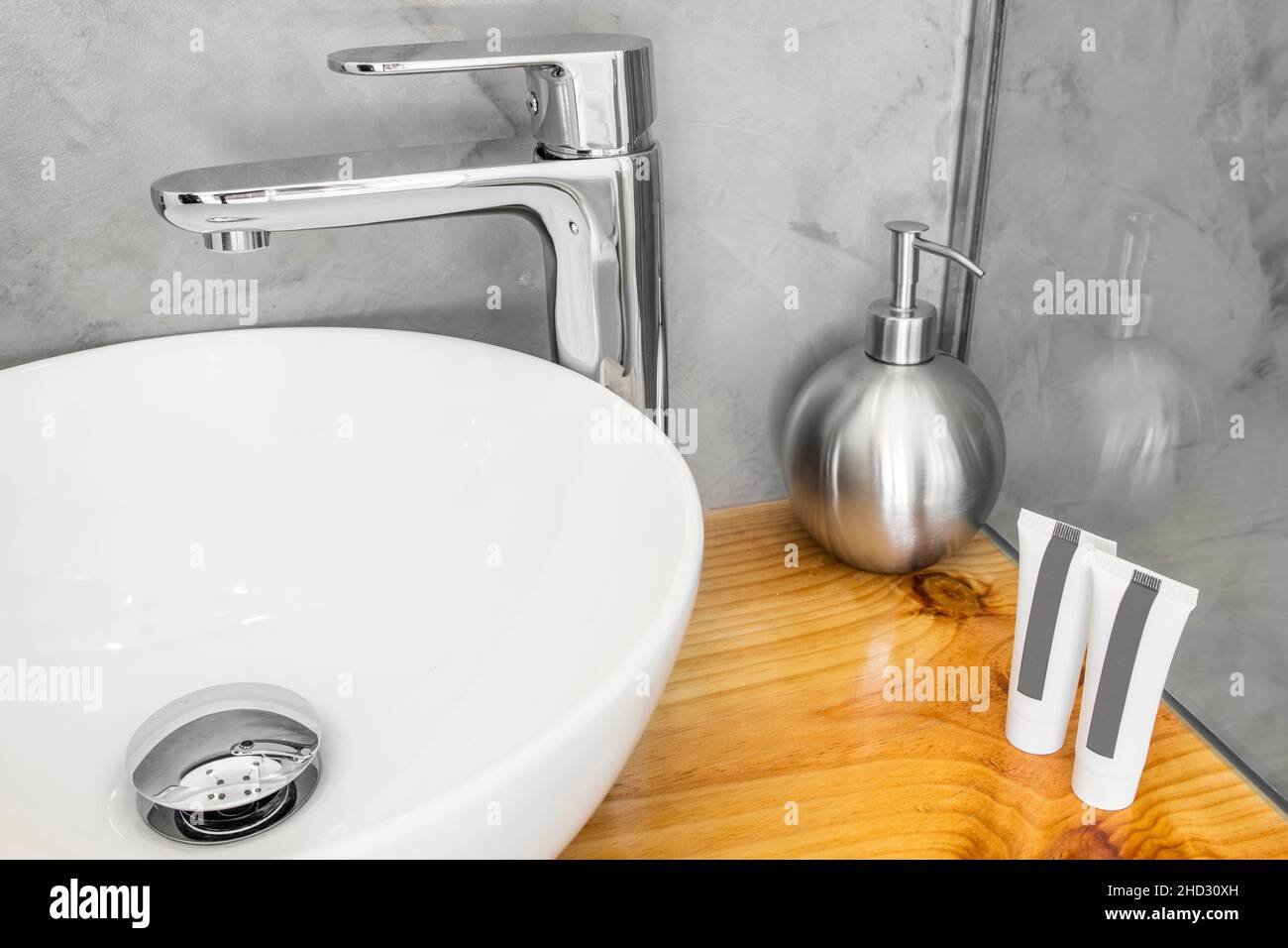 White porcelain sink with stainless steel tap on wooden countertop with