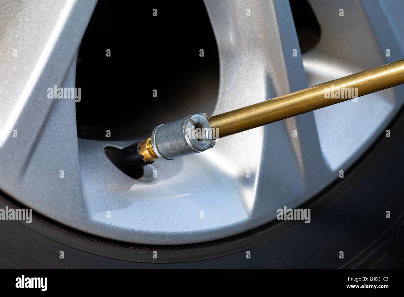 Air chuck on tire valve stem inflating car tire. Vehicle safety, tire wear, fuel mileage and winter checkup concept. Stock Photo