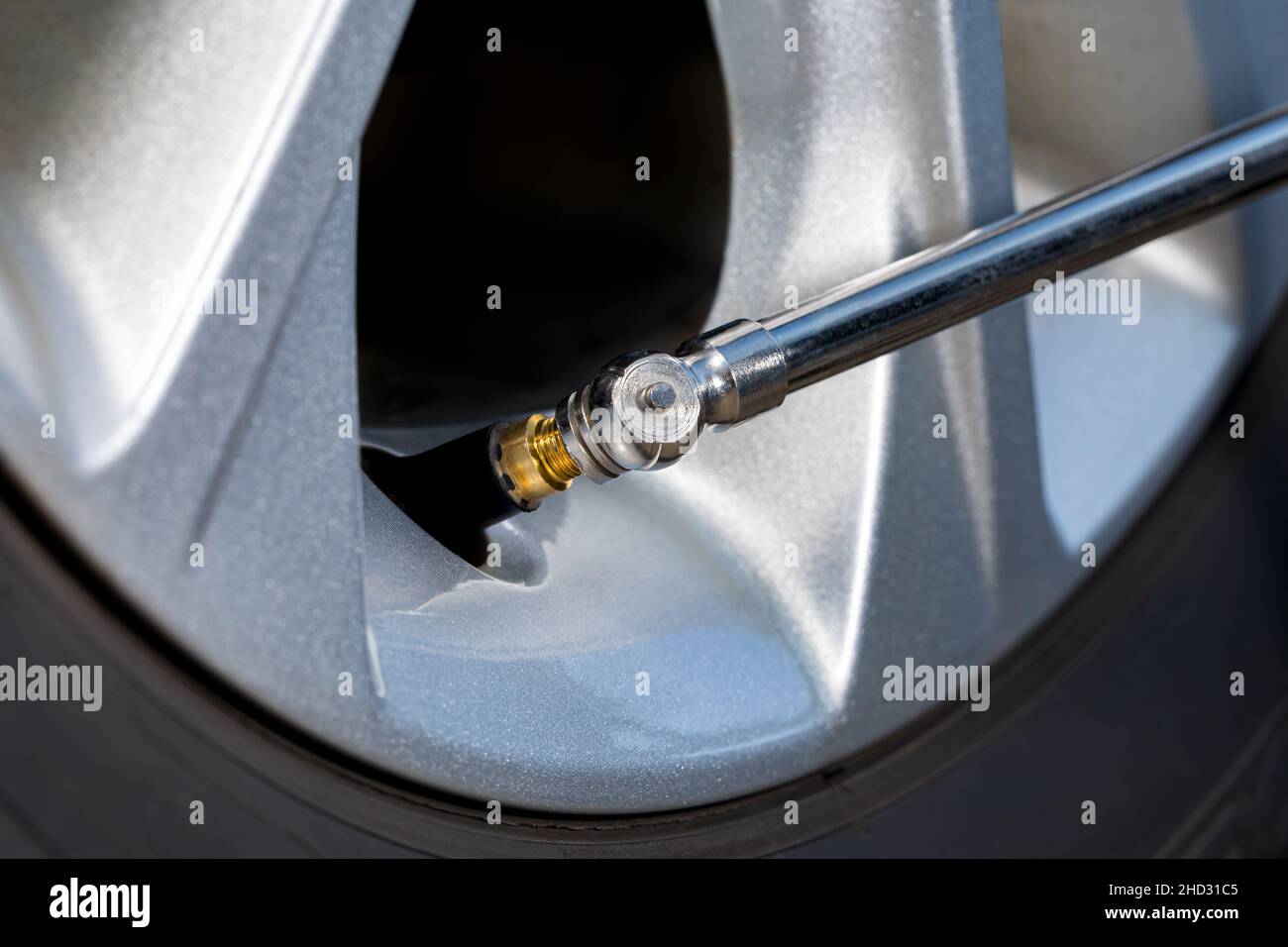 Air pressure gauge on tire valve stem of car wheel. Vehicle safety, tire wear, fuel mileage and winter checkup concept. Stock Photo