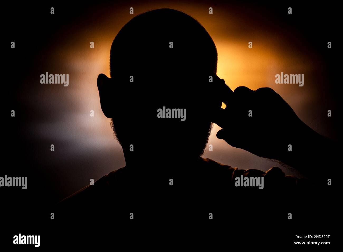 Close-up silhouette of a man's head against a orange background. Salvador, Bahia, Brazil. Stock Photo