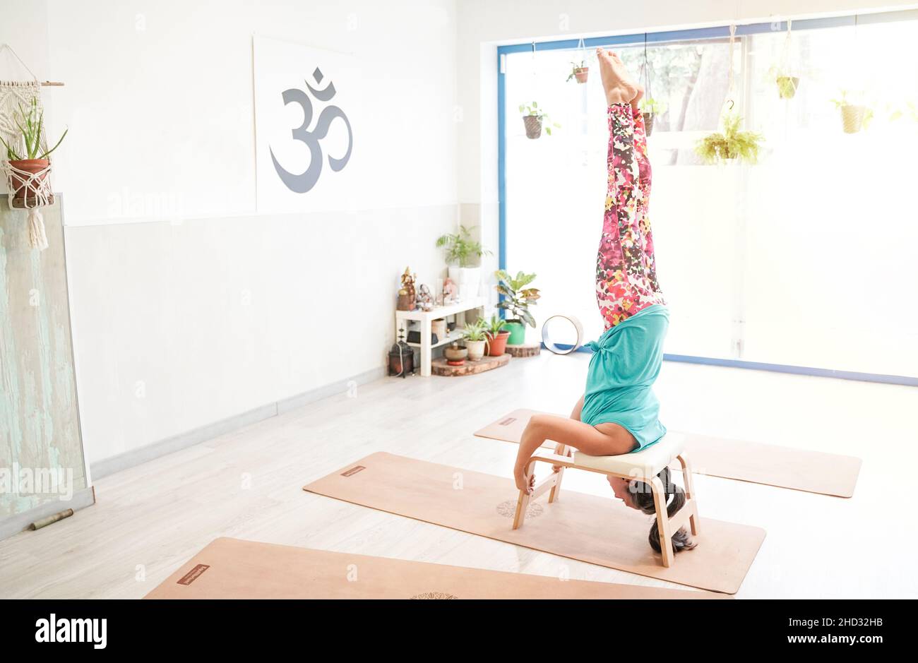 fit woman in headstand using a professional yoga bench. feet up barefoot in Supported Headstand pose, salamba shirshasana Stock Photo
