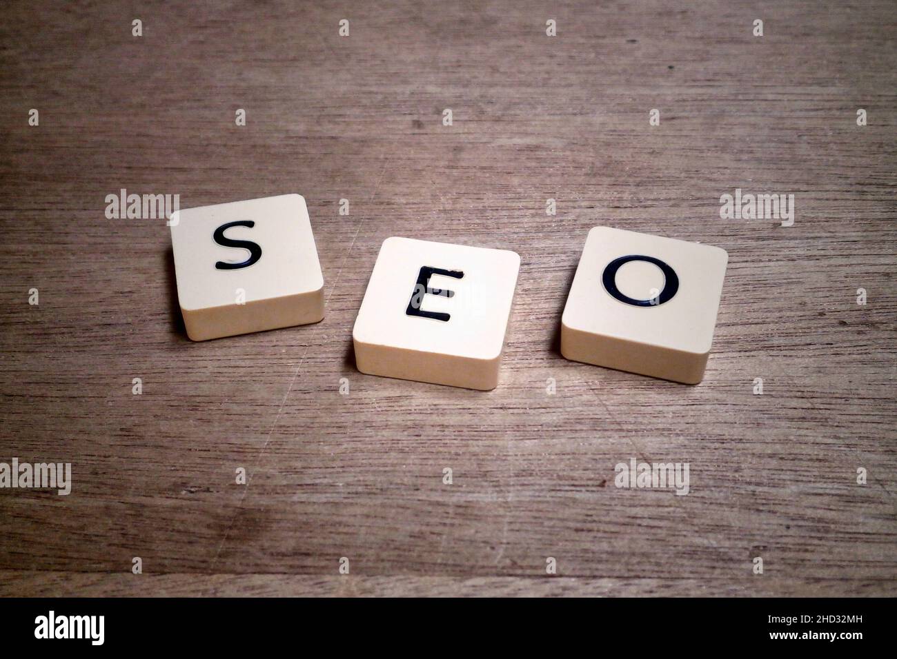 Lettered plastic tiles on a wooden board displaying the acronym SEO. Stock Photo