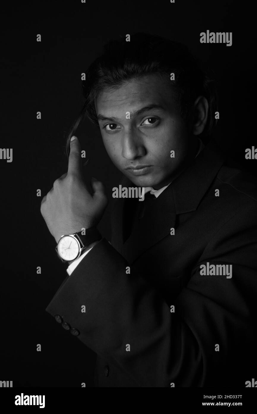 Vertical grayscale shot of an Indian man wearing a classy suit and watch Stock Photo