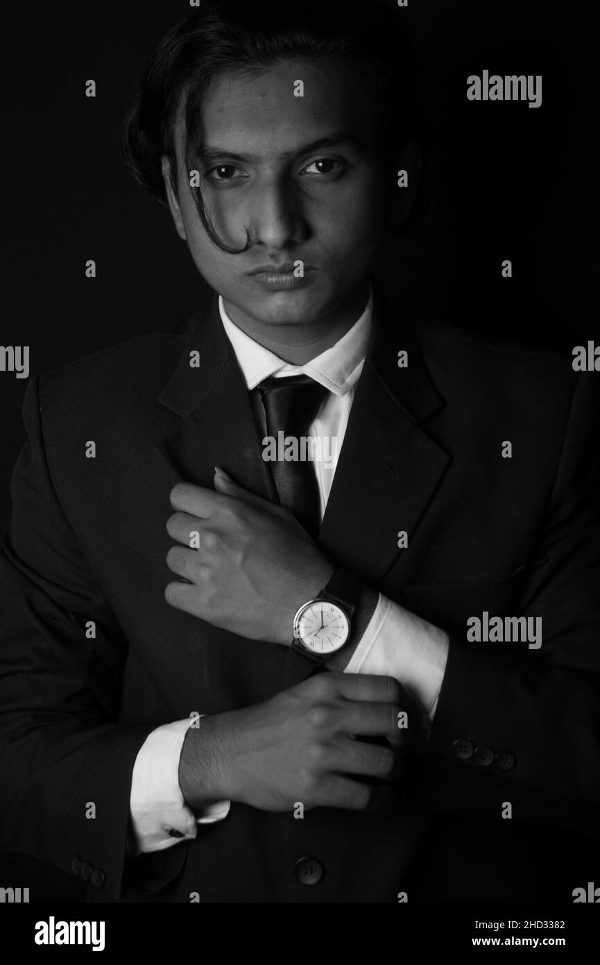 Vertical grayscale shot of an Indian man wearing a classy suit and watch Stock Photo