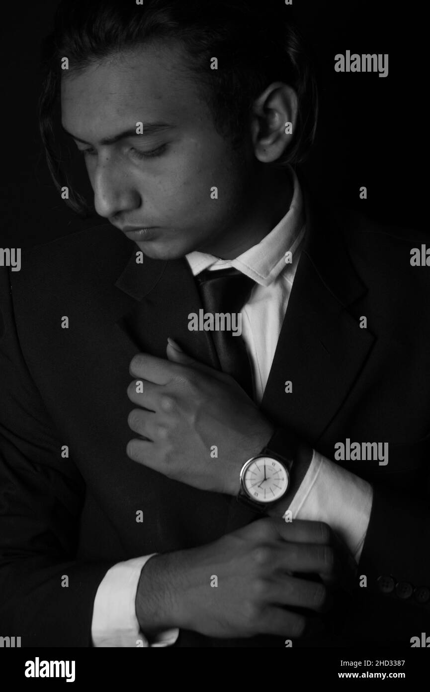 Vertical grayscale shot of an Indian man wearing a classy suit and watch Stock Photo
