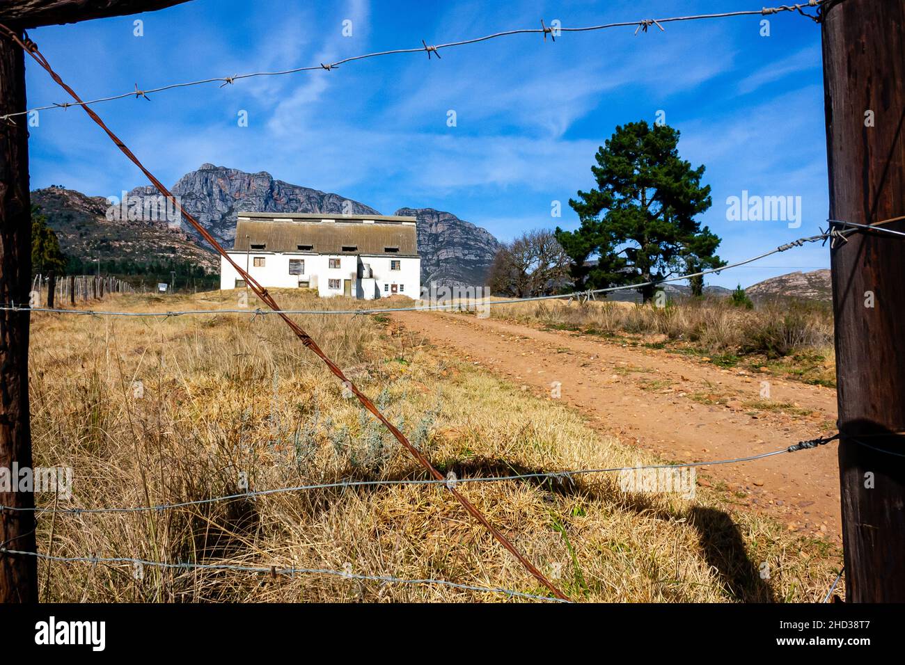 An old abandoned shed with a barbed wire fence in the foreground Stock Photo