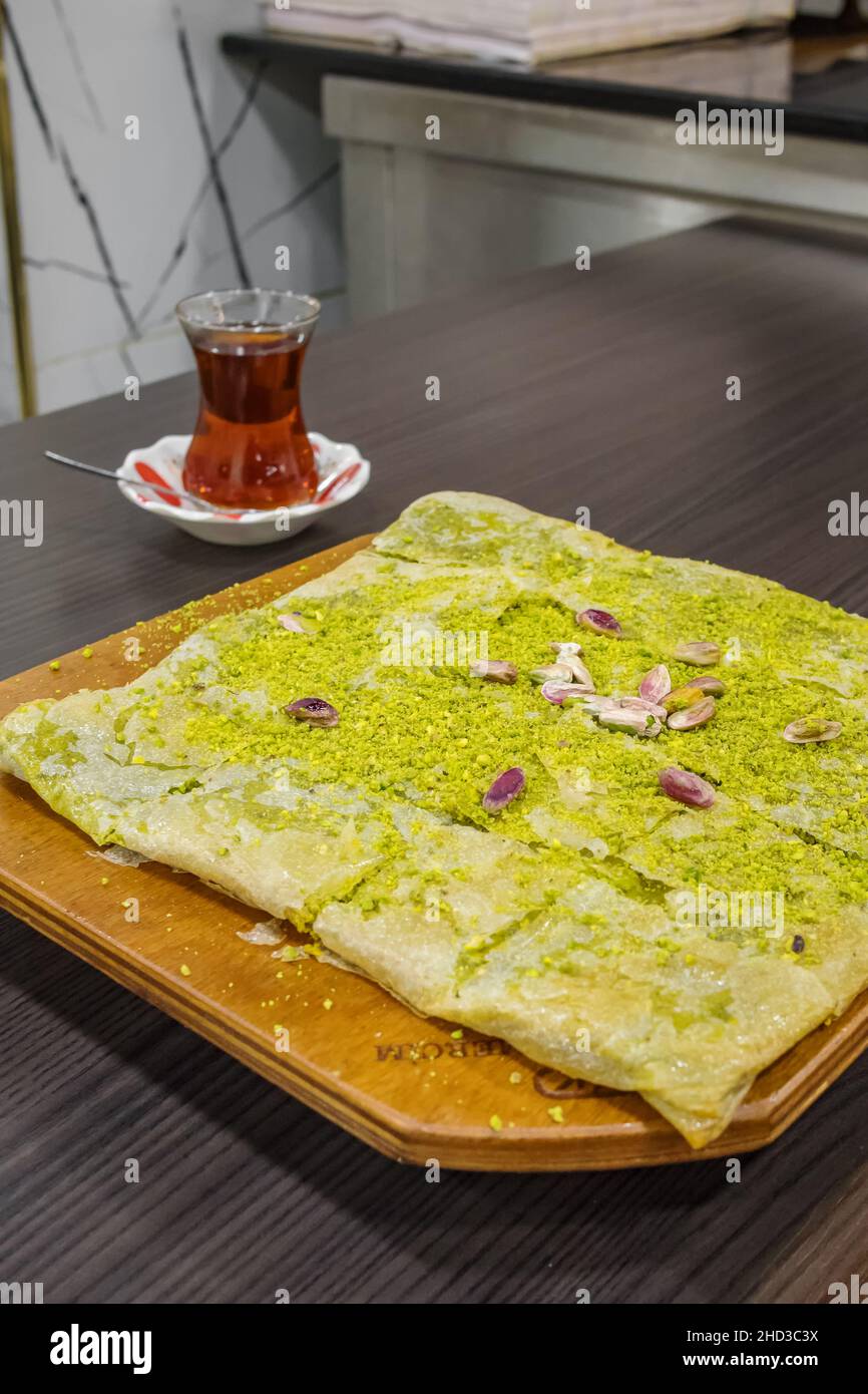 Delicious Turkish pistachio dessert Katmer with glass of tea close-up. Stock Photo