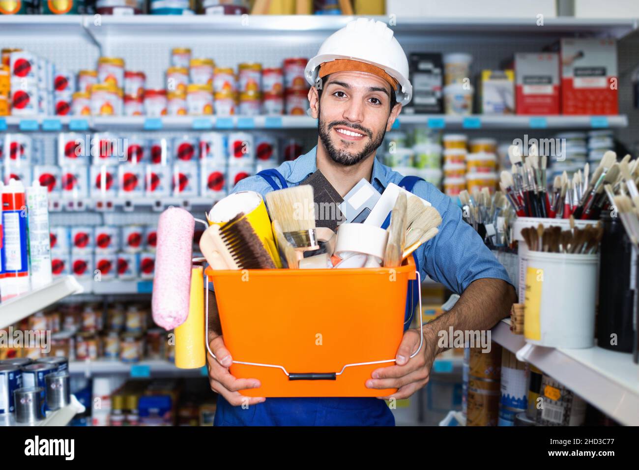 Workman holding basket with picked tools in paint store Stock Photo