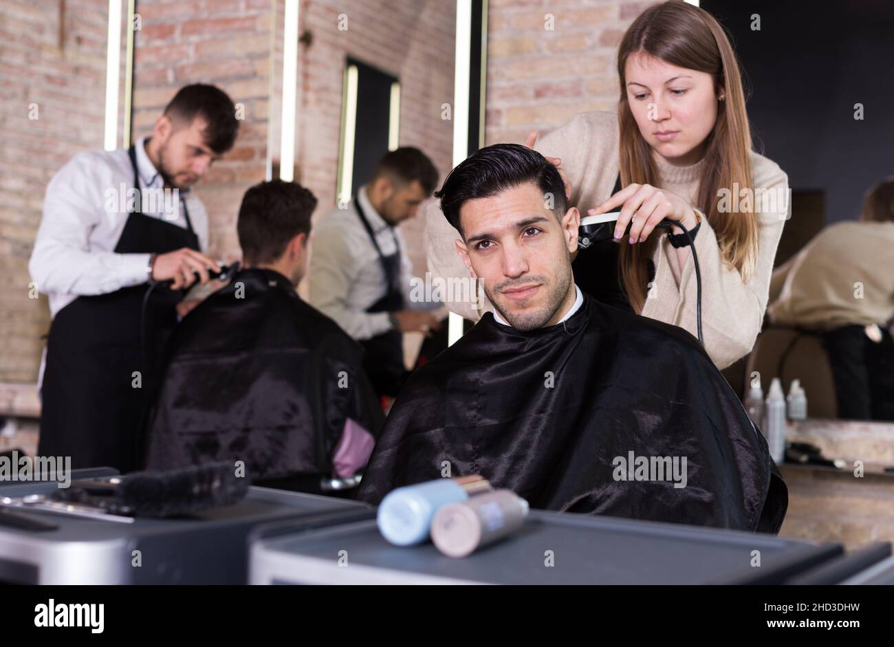 Hairdresser doing styling of guy with electric hair clipper Stock Photo