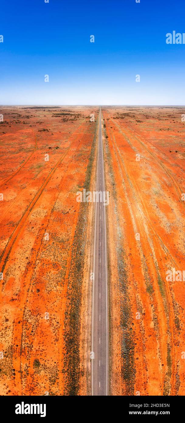 Straight endless barrier highway in Australian outback near Broken Hill - vertical aerial panorama with red soil. Stock Photo