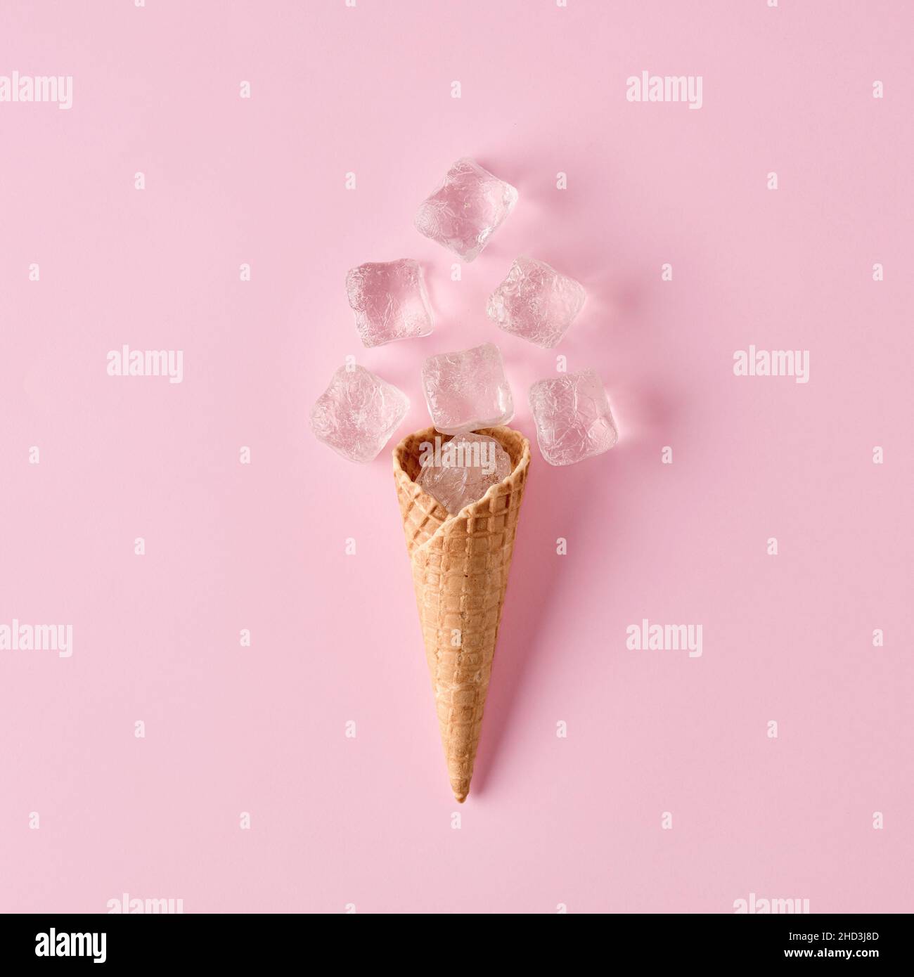 Ice cream waffle cone with ice cubes on pink background. Minimal cold summer food concept. Flat lay. Stock Photo