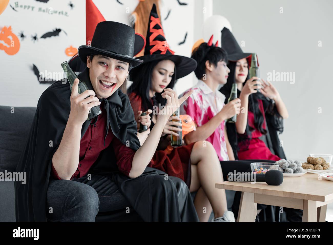 Gang of young Asian in costume witch, wizard with celebrate Halloween party for dance and drink and drunk in the room. Group teen Thai with celebrate Stock Photo