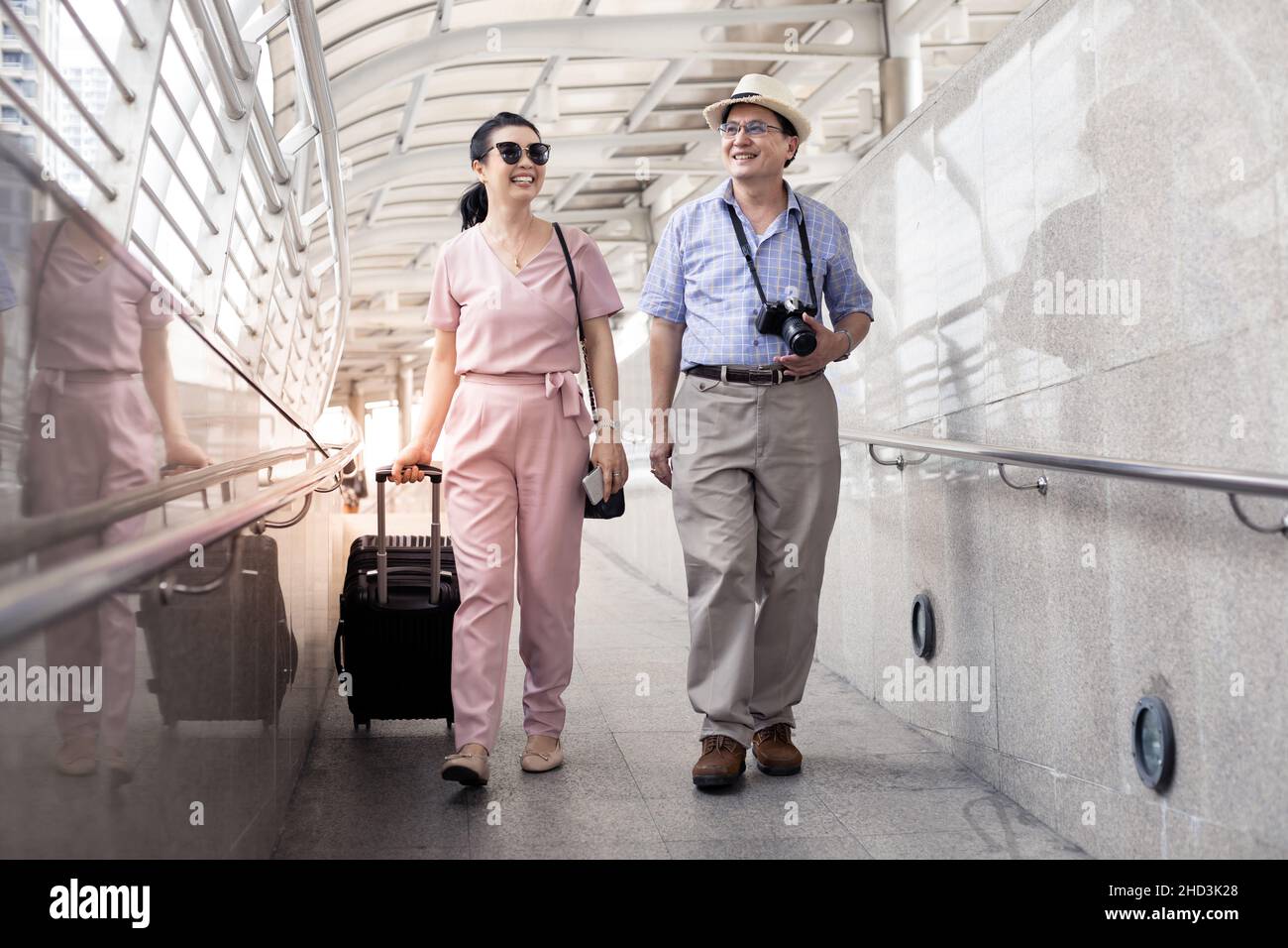Senior Asian couple with a woman dragging a suitcase and talking happily with smiling at the airport to prepare to travel. Happiness of aunts and uncl Stock Photo