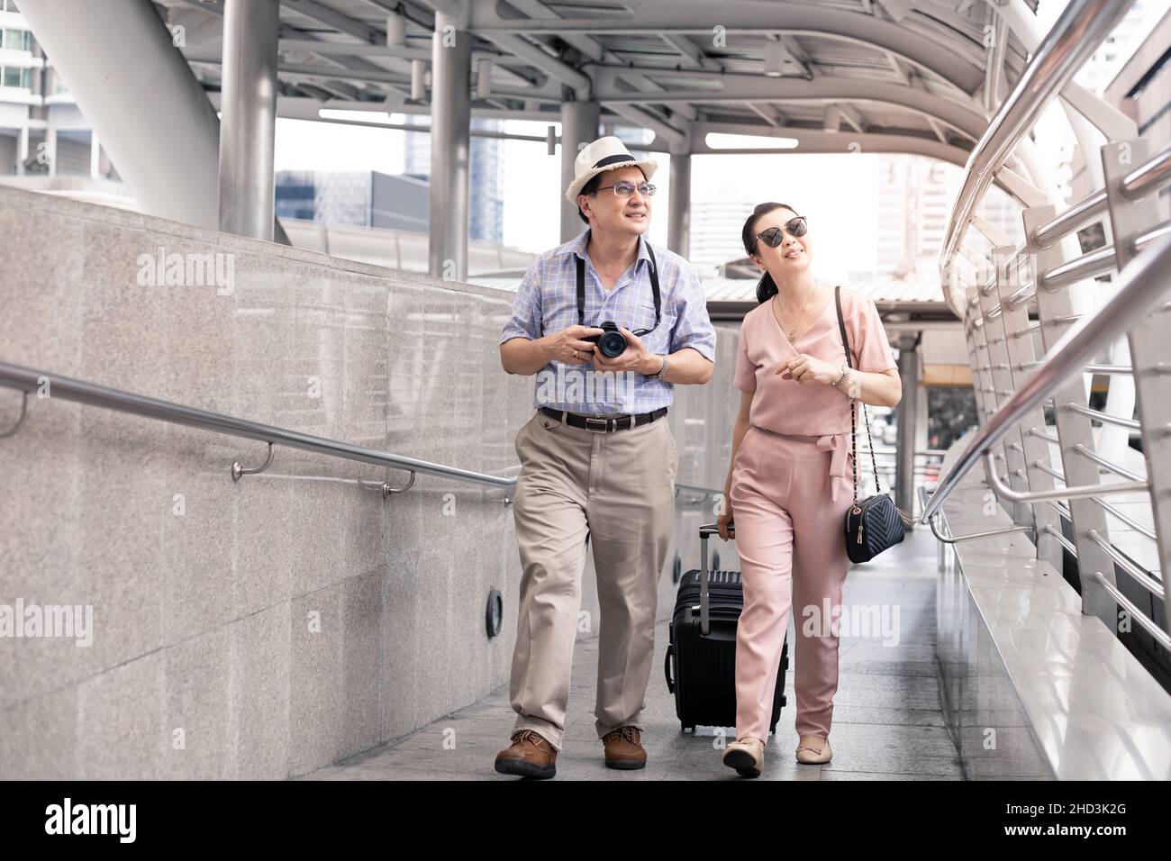 Senior Asian couple with a woman dragging a suitcase and talking happily with smiling at the airport to prepare to travel. Happiness of aunts and uncl Stock Photo