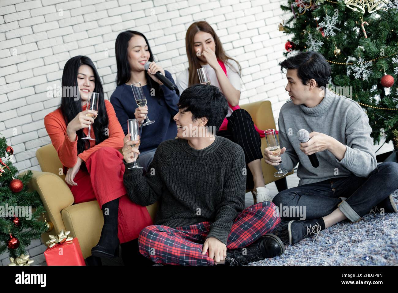 Happy party of young Asian with drink wine and sing a song at home in celebrate Christmas festival. Celebration of new year at house. Merry Christmas Stock Photo
