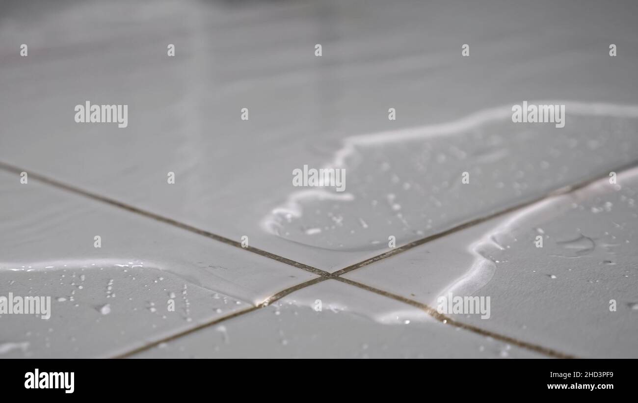 Water flows on floor covering white ceramic tile in bathroom Stock