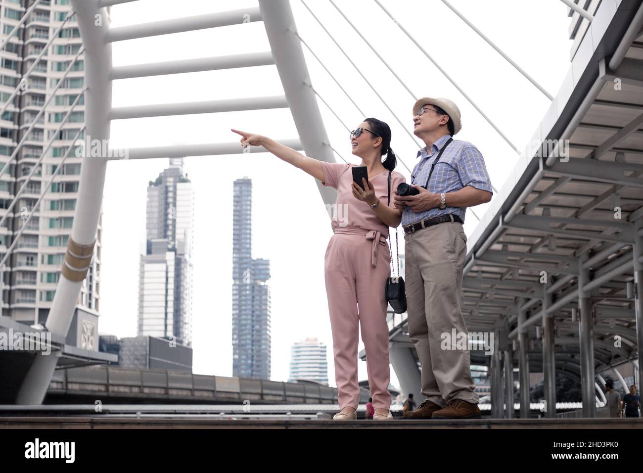 Senior Asian couple pointing to interesting spots at outdoors during the day while on a trip together at landmark in thailand. Senior couple travel co Stock Photo